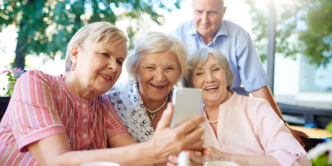 Personnes âgées riant devant un smartphone.